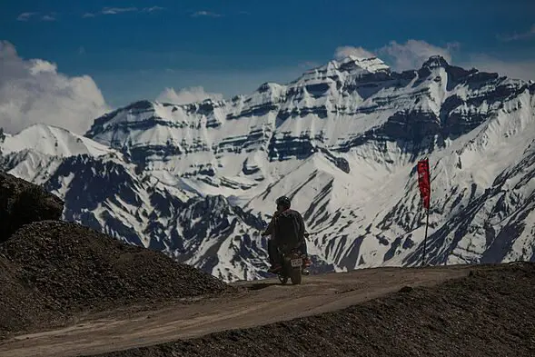 भारत सरकार ने चीन सीमा के पास अरुणाचल प्रदेश में रणनीतिक सीमांत राजमार्ग परियोजना के लिए 6,000 करोड़ रुपये आवंटित किए, भूरे रेत वाले रास्ते पर मोटरसाइकिल चलाता व्यक्ति