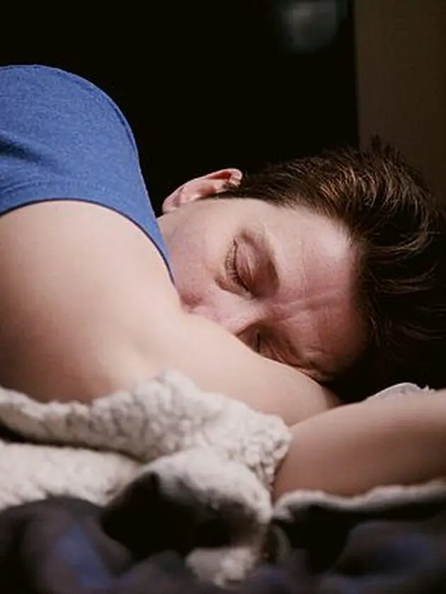 woman in blue shirt lying on bed